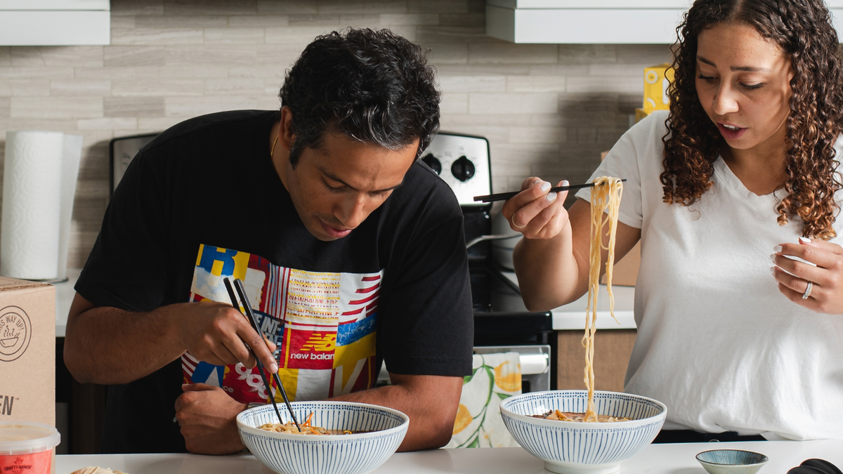 People enjoying Crafty Ramen at a kitchen countertop with a noodle pull.