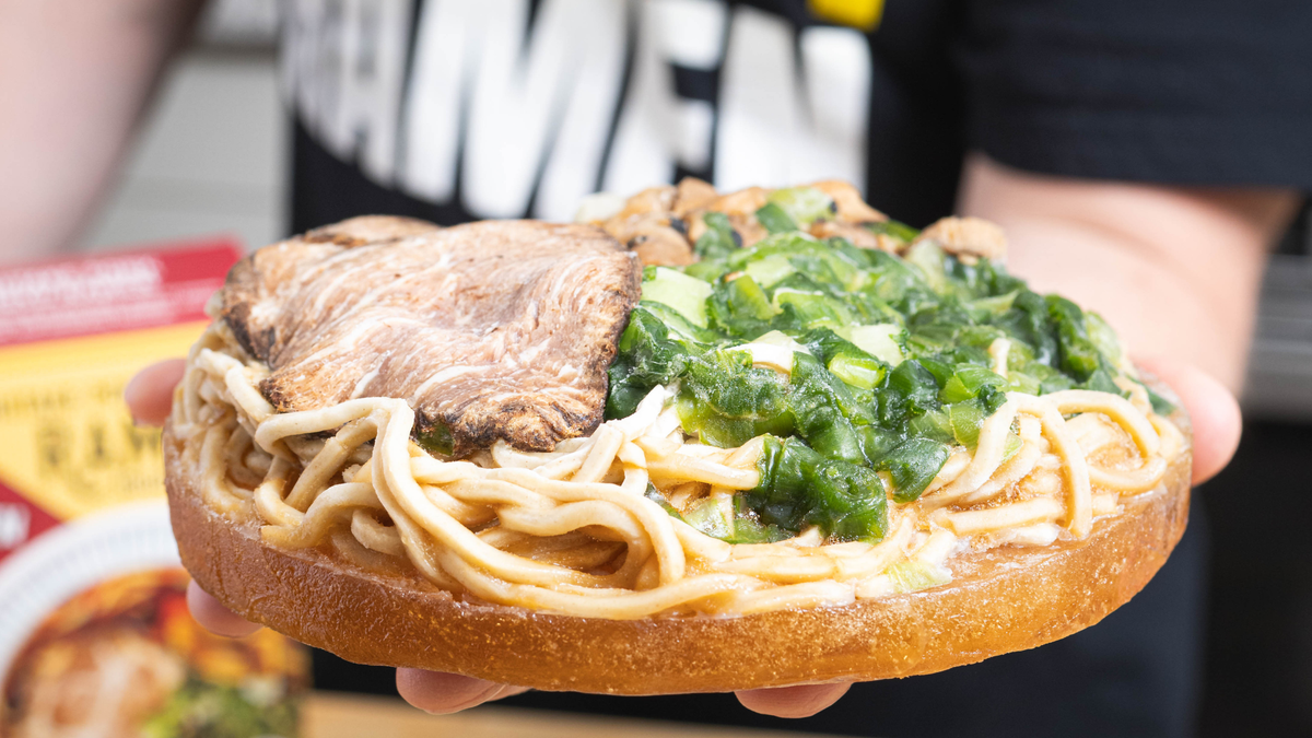 Jared holding a Pork Shoyu Frozen Ramen puck with scratch-made noodles, real bone broth, sliced pork chashu, and green onions, wearing a 'Crafty Ramen' shirt.